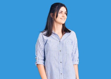 Çizgili tişört giyen, yüzünde gülümseme ve doğal ifadeyle yan yana bakan genç ve güzel bir kız. Kendinden emin gülen. 