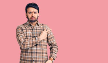 Gündelik kıyafetler giyen genç İspanyol adam endişeli ve gergin bir şekilde işaret ediyor. 