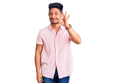 Yakışıklı Latin Amerikalı, günlük tişört giyen, gülümseyen, el ve parmaklarıyla 