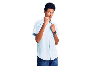 Genç, Afro-Amerikalı, günlük kıyafetler giymiş, yumruk savunma hareketleriyle dövüşmeye hazır, kızgın ve üzgün yüzlü, sorundan korkan. 