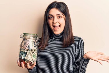 Bahşiş kavanozu tutan genç ve güzel bir kız başarıyı mutlu bir gülümsemeyle kutluyor ve kazanan ifade elini kaldırıyor. 