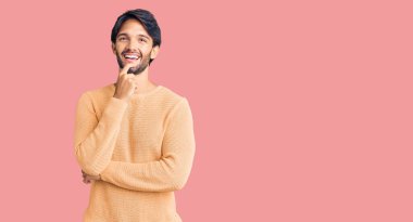 Yakışıklı, sıradan süveter giyen, kameraya kendinden emin, kollarını kavuşturmuş ve çenesini kaldırmış bir şekilde bakan bir İspanyol. Olumlu düşünmek. 