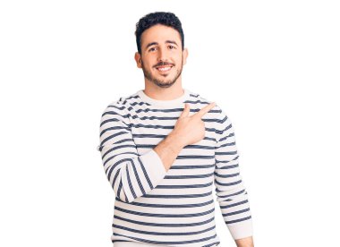 Gündelik kıyafetler giyen, neşeli, yüzünde gülümseme olan genç İspanyol adam mutlu ve doğal bir ifadeyle elini ve parmağını kaldırdı. 