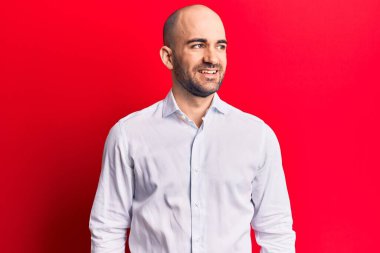 Zarif bir gömlek giyen genç yakışıklı kel bir adam, yan bakmak için, rahat profil pozu doğal bir yüz ve kendinden emin bir gülümseme ile. 