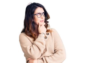 Güzel, genç, esmer, sıradan kıyafetler ve gözlük takan bir kadın bir soru hakkında endişeli ve gergin bir şekilde düşünüyor. 