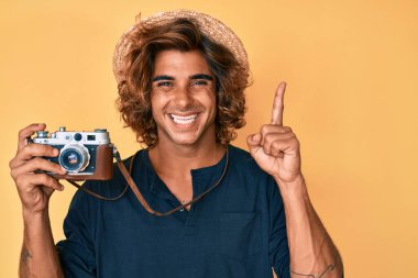 Şapkalı genç İspanyol bir adam elinde klasik bir fotoğraf makinesi tutarken bir fikre ya da soru işaretine şaşırdı. 