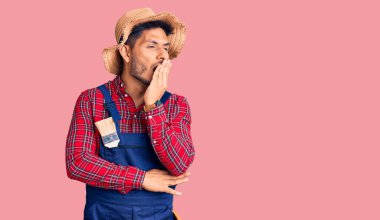 Yakışıklı Latin Amerikalı, tamirci üniforması giyen genç adam ağzıyla esnemekten sıkılmış. Huzursuz ve uykulu.. 