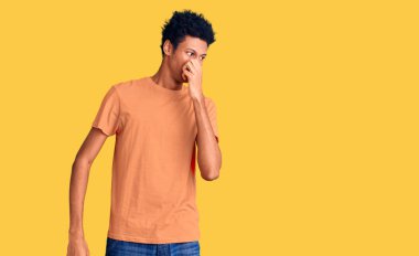 Genç, Afro-Amerikan bir adam günlük giysiler giymiş pis ve iğrenç bir koku alıyor, dayanılmaz bir koku, parmakları burnunda nefesini tutuyor. Kötü kokuyor. 