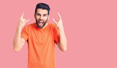 Sakallı, sıradan tişörtlü, çılgın bir ifadeyle bağıran genç yakışıklı adam elleri havada rock sembolü yapıyor. Müzik yıldızı. ağır müzik konsepti. 