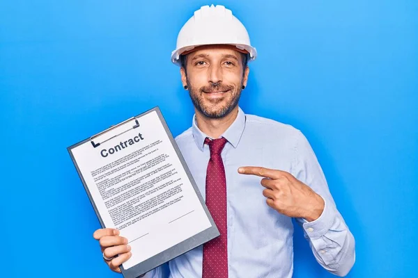 Joven Hombre Guapo Usando Arquitecto Hardhat Celebración Contrato Documento Sonriendo —  Fotos de Stock