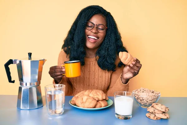 Młoda Afroamerykanka Jedząca Śniadanie Trzymająca Rogalika Uśmiechnięta Śmiejąca Się Głośno — Zdjęcie stockowe