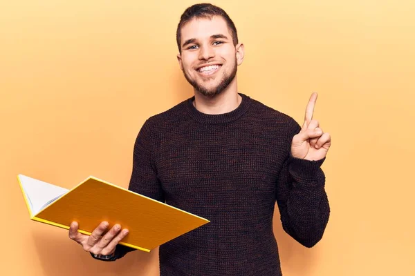 Jovem Homem Bonito Lendo Livro Sorrindo Com Uma Ideia Pergunta — Fotografia de Stock