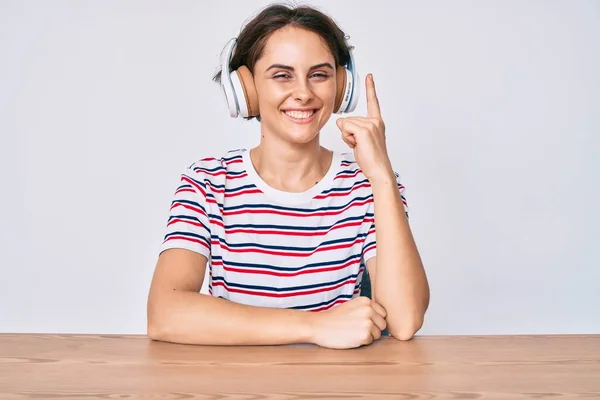 Jeune Femme Hispanique Utilisant Des Écouteurs Assis Sur Table Pointant — Photo