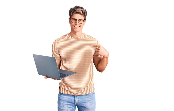 Jovem Homem Bonito Usando Óculos Segurando Laptop Apontando Dedo Para — Fotografia de Stock