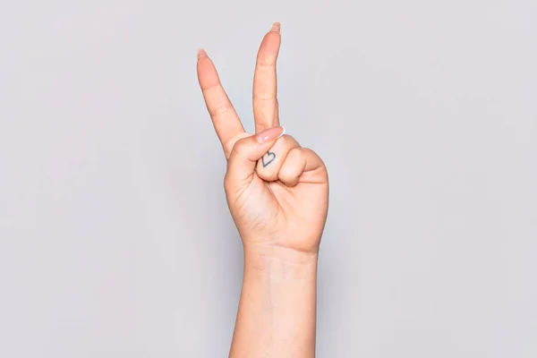 Hand of caucasian young woman counting number 2 showing two fingers, gesturing victory and winner symbol