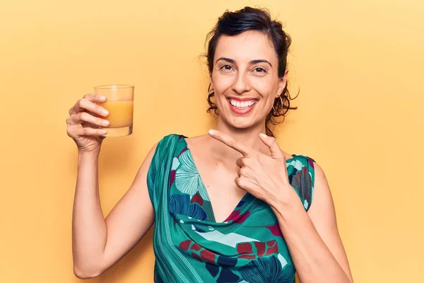 아름다운 스페인 여자가 오렌지 주스를 마시며 손가락으로 행복하게 가리키고 — 스톡 사진
