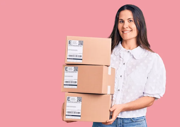 Young Beautiful Brunette Woman Holding Delivery Cardboard Package Looking Positive — Stock Photo, Image
