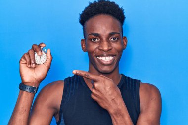 Kronometre tutan genç Afrikalı Amerikalı adam mutlu bir şekilde elini ve parmağını gösterdi. 