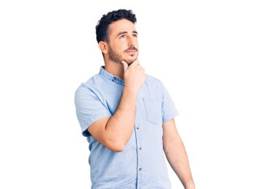 Gündelik kıyafetler giyen genç İspanyol bir adam ciddi bir yüz ifadesi, eli çenesinde soru soran, kafa karıştırıcı bir fikir hakkında düşünceli. 