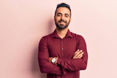 Gündelik kıyafetler giyen, kollarını kavuşturup kameraya gülümseyen genç İspanyol adam. pozitif kişi. 