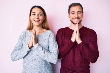 Gündelik giysiler giyen güzel bir çift ellerinin birbiri ile dua ederek af diliyor.. 