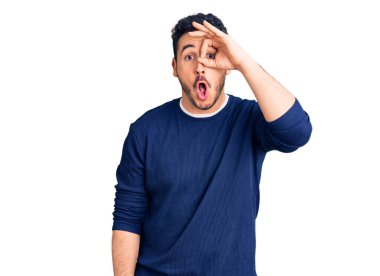 Gündelik kıyafetler giyen genç İspanyol adam şaşırmış yüz ifadesiyle şok olmuş, parmaklarından bakan gözler. İnançsız ifade. 