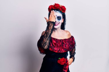 Meksika 'da ölü makyajı yapan genç bir kadın bir gözünü eliyle kapatıyor, yüzünde kendine güvenen bir gülümseme ve şaşırtıcı bir duygu var.. 