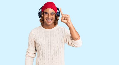 Genç İspanyol adam müzik dinlerken kulaklık takıyor ve başarılı bir fikri işaret ediyor. Heyecanlı ve mutlu. Bir numara.. 