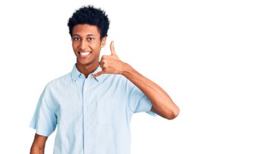 Genç Afro-Amerikan adam günlük giysiler giyip gülümsüyor telefonla el ve parmaklarıyla jest yapıyor telefonda konuşuyor gibi. iletişim kavramları. 