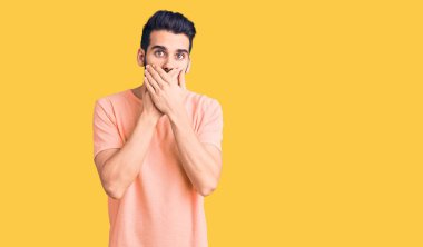 Sıradan tişörtler giyen sakallı genç yakışıklı adam yanlışlıkla elleri ile ağzını kapatırken şok oldu. gizli kavram. 