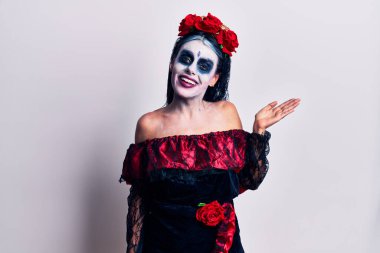 Meksika makyajlı genç bir kadın. Gülümsüyor, mutlu bir şekilde sunuyor ve avuç içi kameraya bakıyor.. 