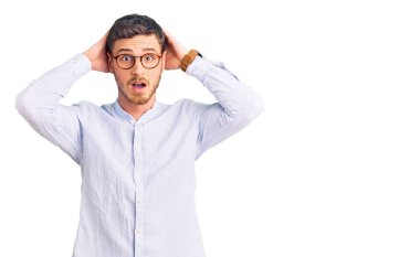 Zarif bir iş gömleği ve gözlüklü yakışıklı genç adam çıldırmış ve elleri başında korkmuş, ağzı açık şoktan korkmuş ve şaşırmış. 