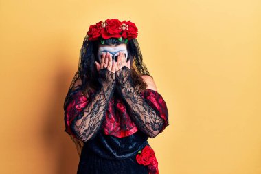 Sarıya boyanmış ölü kostümü giyen genç bir kadın. Ağlarken suratını ellerle kapatan üzgün bir ifade. depresyon kavramı. 