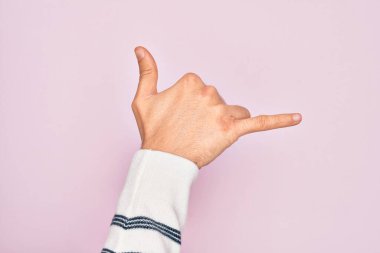 Kafkas genci parmaklarını izole edilmiş pembe arka planda gösteriyor Hawaii Shaka selamlama hareketi, telefon ve iletişim sembolü.