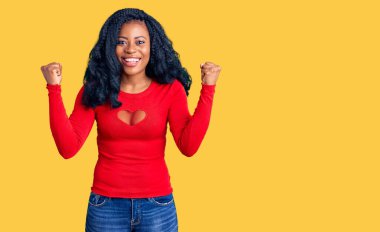 Güzel afro-amerikan kadın gündelik giysiler giyip şaşkınlık ve şaşkınlık içinde kolları açık ve gözleri açık bir şekilde başarıyı kutluyor. Kazanan konsept. 
