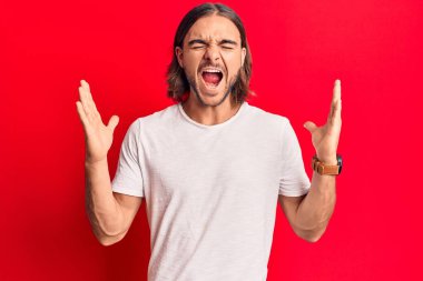 Gündelik kıyafetler giyen genç, çılgın ve çılgın başarıyı kutlayan kollarını kaldırmış, gözlerini kapatmış heyecanlı çığlıklar atan yakışıklı bir adam. Kazanan konsept 