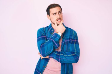 Gündelik kıyafetler giyen genç yakışıklı bir adam bir soru hakkında endişeli ve gergin bir şekilde düşünüyor. 