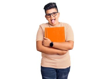 Küçük çocuk elinde gözlüklü, dilini dışarı çıkaran komik bir ifadeyle kitap tutuyor. duygu kavramı. 