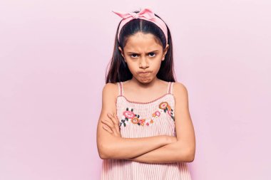 Gündelik kıyafetler giyen, kuşkucu ve gergin güzel bir kız çocuğu. Yüzünde çapraz kollarla onaylamayan bir ifade var. negatif kişi. 