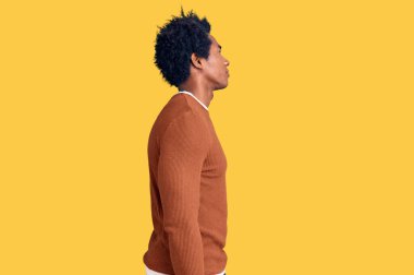 Afro saçlı, sıradan kıyafetler giyen, rahat bir görünüm takınan, kendine güveni olan yakışıklı Afro-Amerikan erkeği.. 