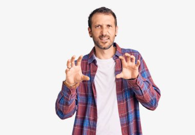 Genç, yakışıklı, günlük kıyafetler giymiş komik gülüyor. Pençe hareketlerini kedi gibi yapıyor. Agresif ve seksi bir ifade. 