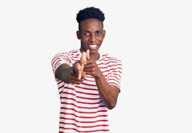 Sıradan kıyafetler giymiş genç Afro-Amerikalı adam mutlu ve komik yüzüyle kamerayı işaret ediyor. iyi enerji ve titreşimler. 