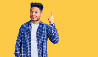 Yakışıklı Latin Amerikalı, günlük gömlekler giyen genç adam başarılı bir fikirle işaret ediyor. Heyecanlı ve mutlu. Bir numara.. 