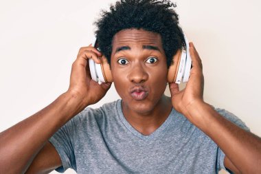 Yakışıklı Afro saçlı, kulaklık takmış, güzel ve seksi bir şekilde öpüşürken kameraya bakan Afro-Amerikan bir adam. aşk ifadesi. 