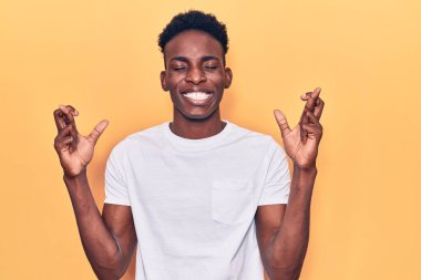 Genç Afro-Amerikalı sıradan kıyafetler giyen, umut ve gözlerin kapalı bir şekilde gülümseyerek el işareti yapan genç bir adam. Şans ve batıl inançlar. 