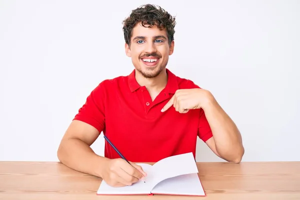 Joven Hombre Caucásico Con Pelo Rizado Escribiendo Cuaderno Sentado Mesa —  Fotos de Stock