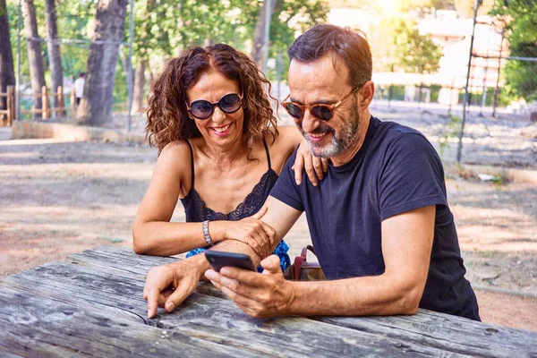 Casal Meia Idade Sorrindo Feliz Usando Smartphone Sentado Banco Parque — Fotografia de Stock