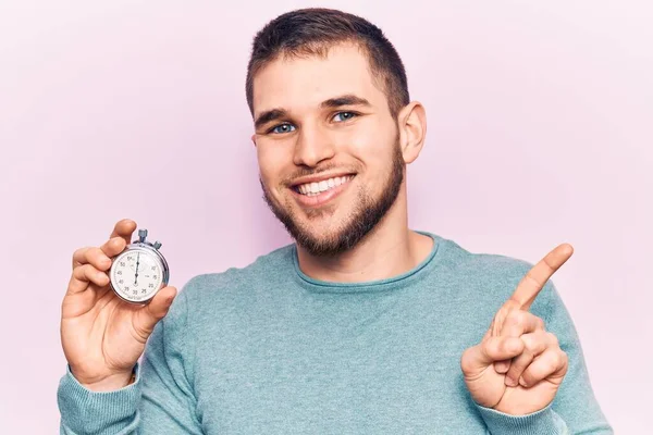 Joven Hombre Guapo Sosteniendo Cronómetro Sonriendo Feliz Señalando Con Mano — Foto de Stock