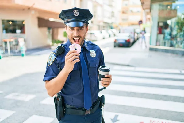 Młody Przystojny Policjant Mundurze Policyjnym Uśmiecha Się Szczęśliwy Jedzenie Pączków — Zdjęcie stockowe