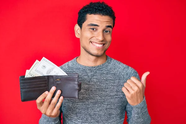 Joven Hombre Hispano Guapo Sosteniendo Billetera Con Dólares Apuntando Pulgar — Foto de Stock